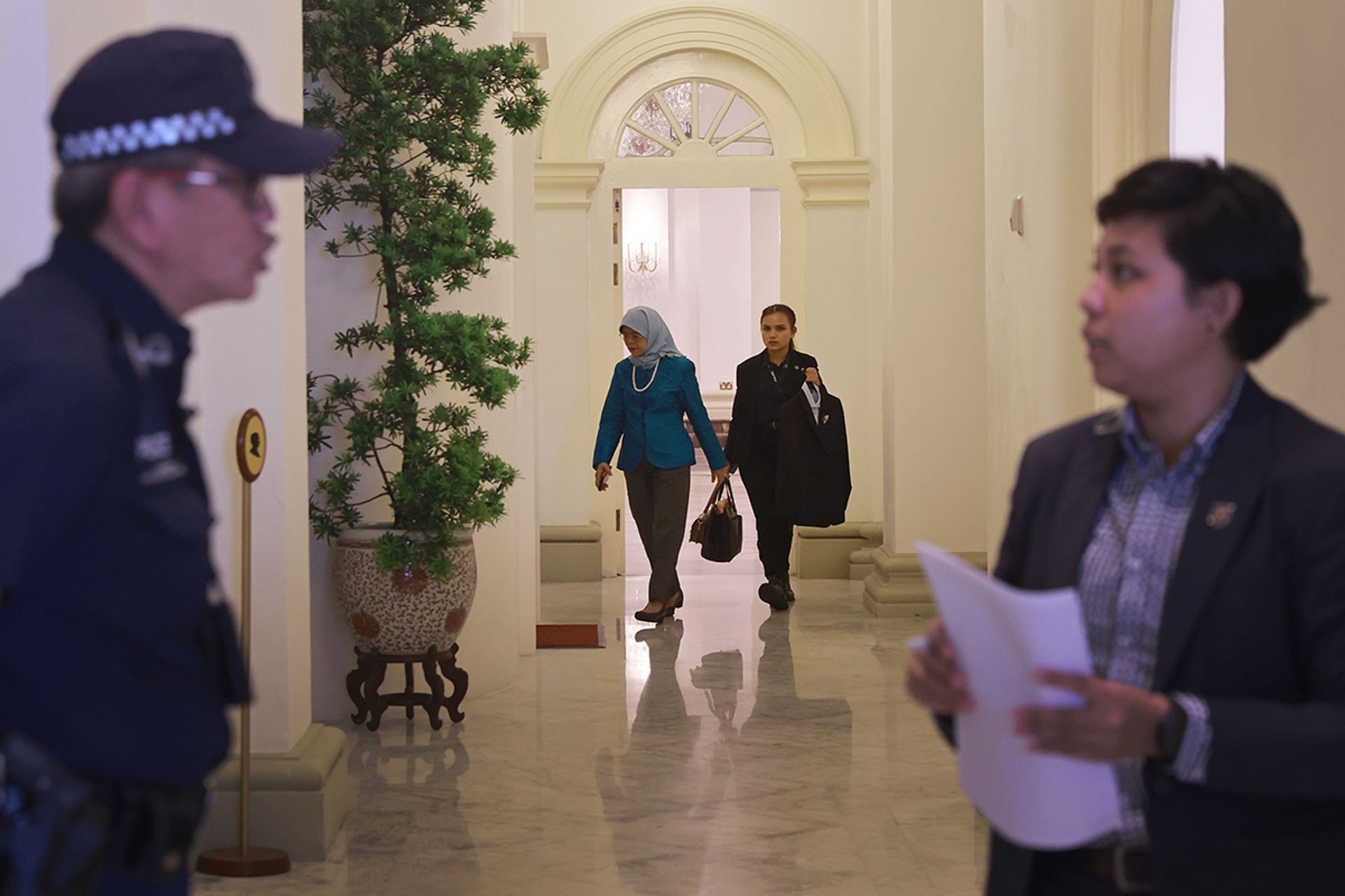 President Halimah is accompanied by a security officer as she walks to an engagement at the Istana on June 5, 2023. ST PHOTO: JASON QUAH