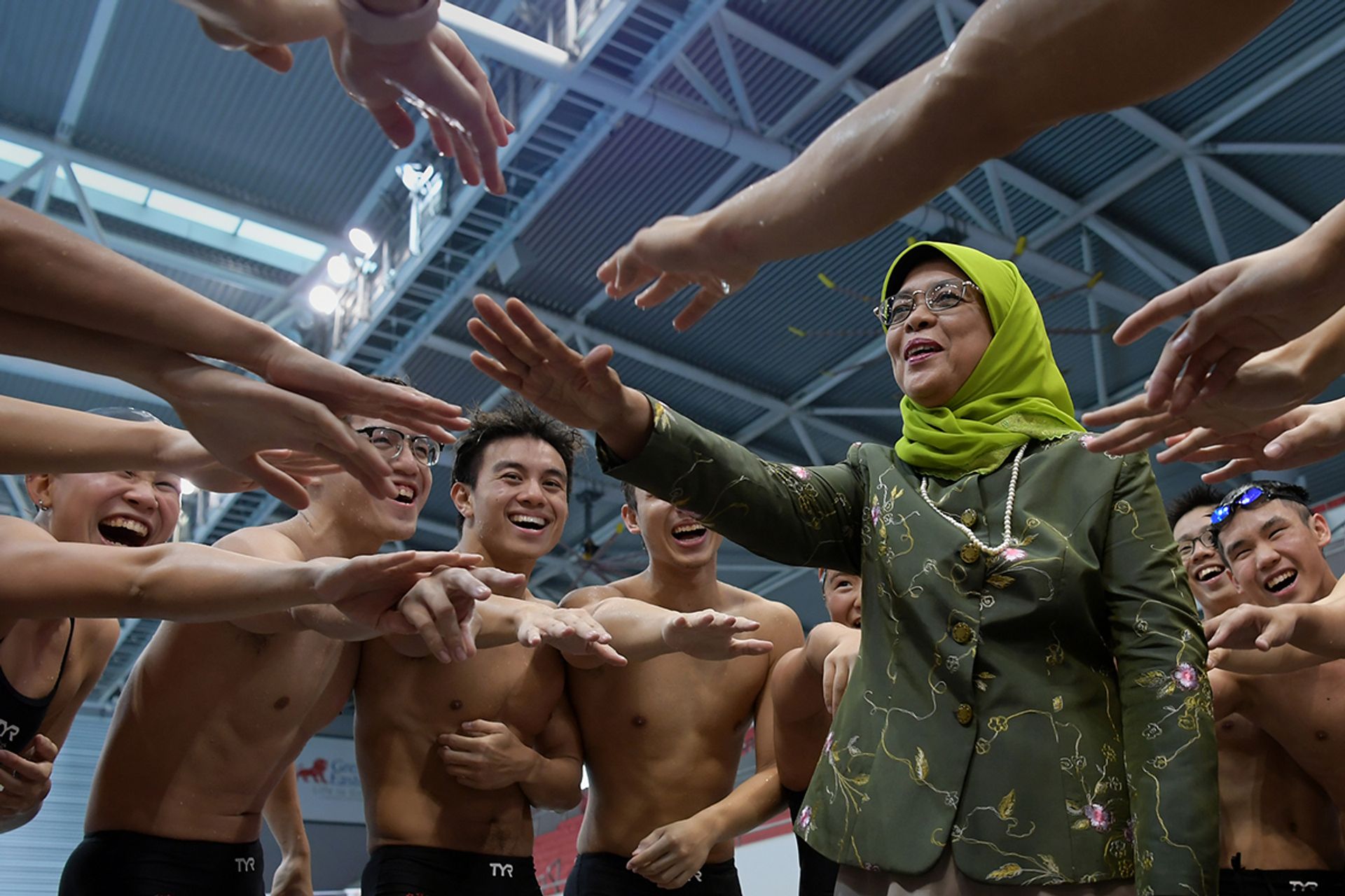 President Halimah taking part in a cheer with Team Singapore swimmers at the OCBC Aquatic Centre on June 5, 2018. She was visiting Team Singapore athletes – from swimming, boccia, pencak silat, water polo and sailing – who were preparing for the 2018 Asian Games held in Jakarta and Palembang, Indonesia. ST PHOTO: NG SOR LUAN
